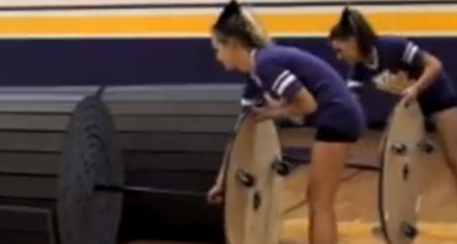 Cheerleaders wheeling Mat Mover IIs across a gym floor between routines